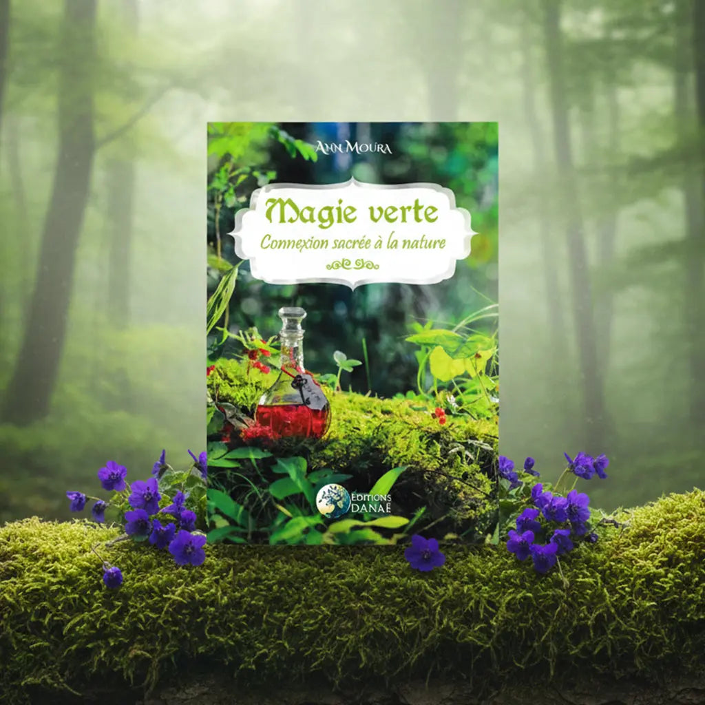 Livre Magie Verte Connexion Sacrée à la Nature d'Ann Moura posé sur de la mousse, illustré d'une fiole de potion rouge et de fleurs violettes.