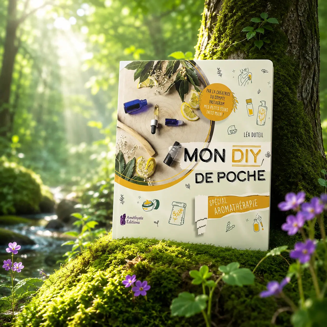 Livre Mon DIY de Poche Spécial Aromathérapie - Léa Duteil sur mousse sacrée au pied d'un arbre, entouré de fleurs violettes sous des rayons de soleil magiques.