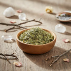 Feuilles de myrthe séchées émiettées dans une coupelle en bois, sur table rustique avec branches, cristaux et pétales.