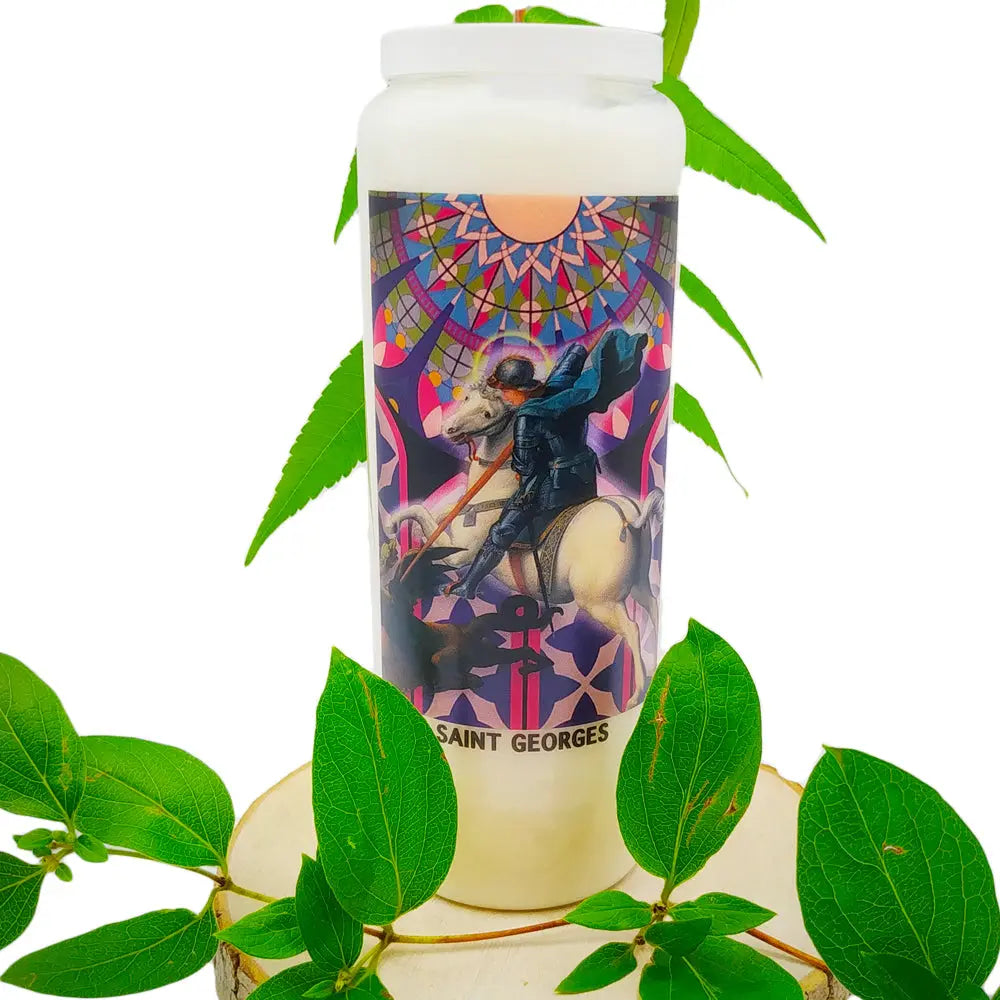 Bougie neuvaine blanche Saint Georges avec illustration religieuse colorée, posée sur un support bois entouré de feuilles vertes.