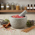 Grains d'encens de résine Notre-Dame de Fatima (rose vif) dans un mortier en granit gris, entouré de brins de lavande, de bâtons de cannelle et de bâtonnets d'encens.