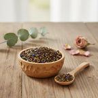 Coupelle en bois remplie de grains d’encens Notre Dame des Victoires multicolores avec petite cuillère sur table en bois.
