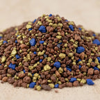 Gros plan sur des grains d’encens Notre Dame des Victoires bruns, dorés et bleus sur fond clair.