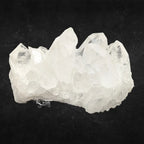 Amas de cristal de roche quartz blanc aux grandes pointes pyramidales translucides sur fond noir.