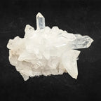 Amas de pointes de cristal de roche translucides et blanches aux formes géométriques sur un fond noir contrasté.