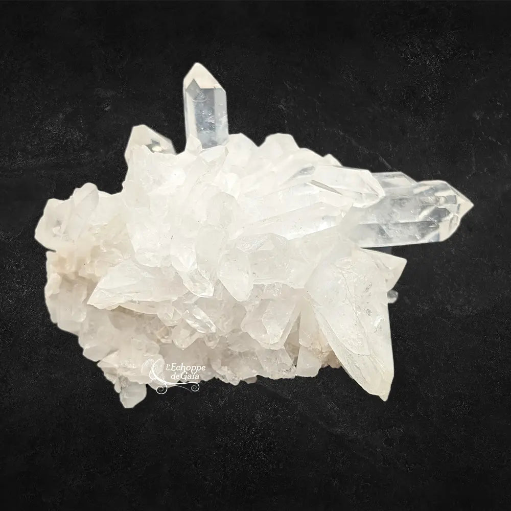 Amas de pointes de cristal de roche translucides et blanches aux formes géométriques sur un fond noir contrasté.