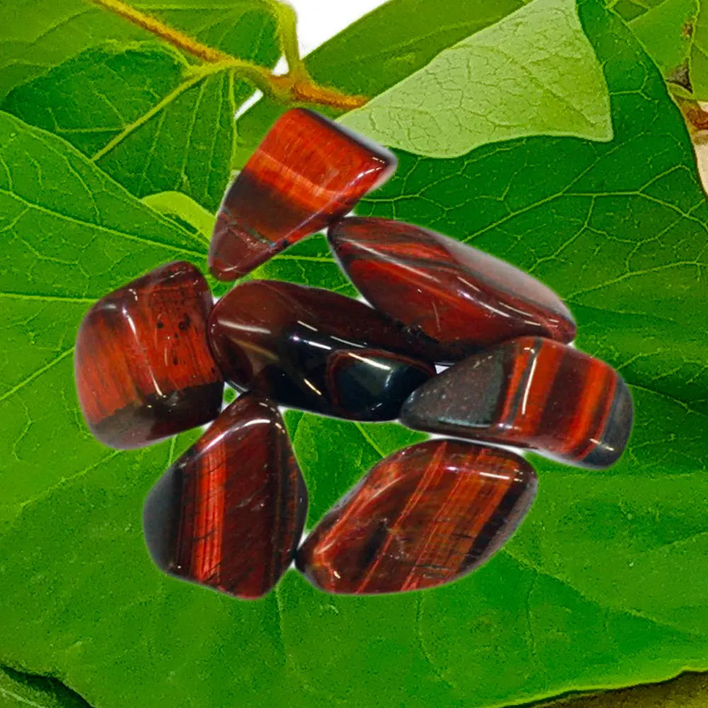 Pierre d'œil de taureau roulée aux reflets chatoyants et soyeux, présentant des bandes horizontales dans des tons de brun rouge et de terracotta, posée sur une tranche de bois naturel.