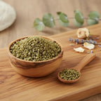 Grains d'encens de résine Or, de couleur vert olive intense, dans un petit bol en bois d'olivier avec cuillère, sur une planche de bois claire.
