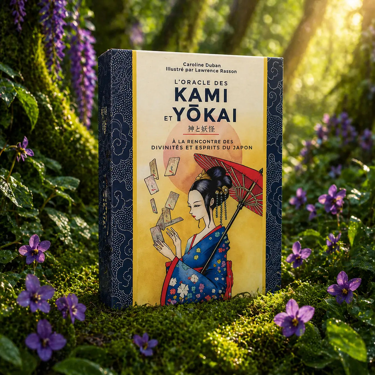 Coffret illustré L'Oracle des Kami et Yôkai de Caroline Duban posé dans la mousse, montrant une femme en kimono avec une ombrelle rouge sous un soleil levant.