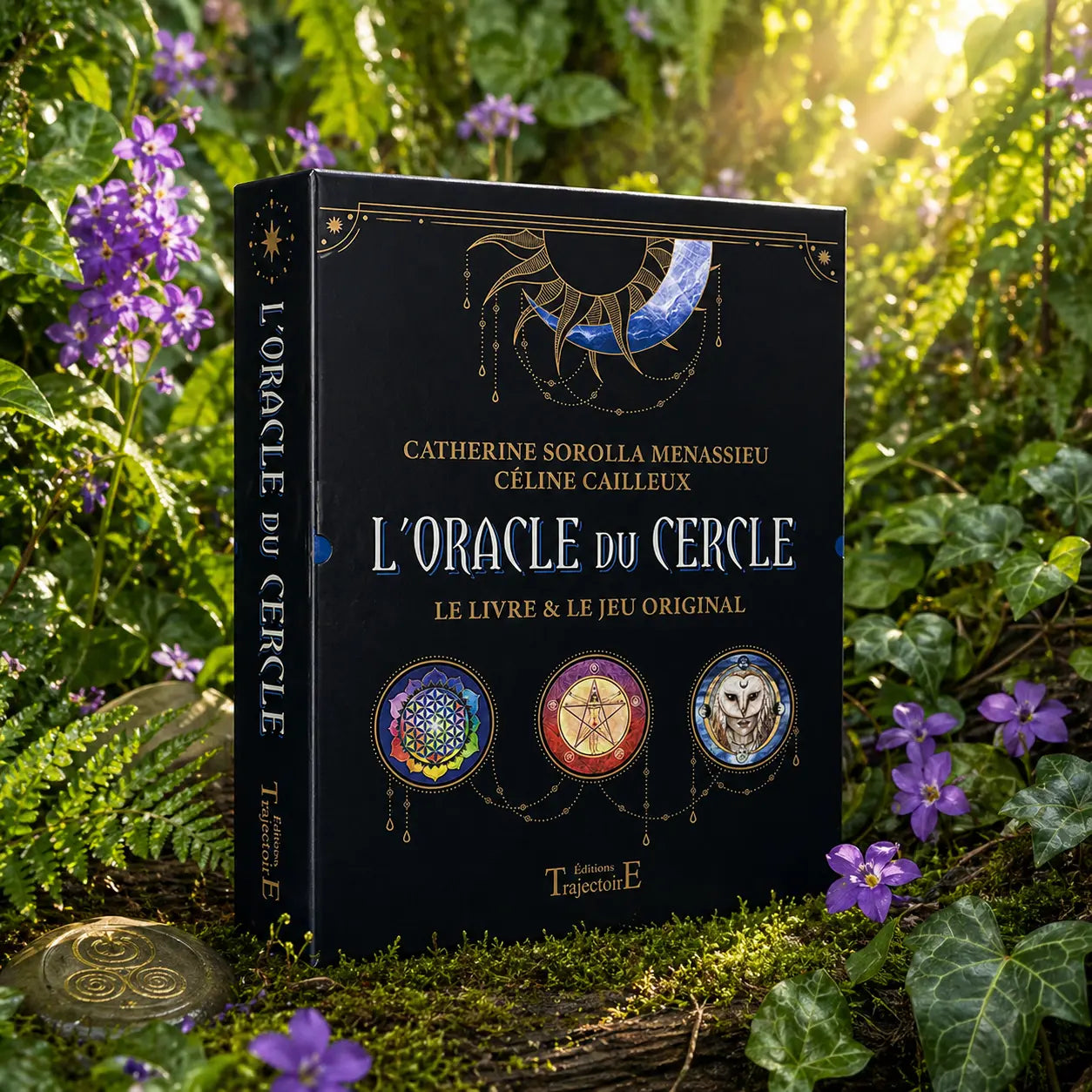 Coffret noir L'Oracle du Cercle de Catherine Sorolla Menassieu posé dans la mousse forestière, orné de trois médaillons illustrant une fleur de vie, un pentagramme et une chouette.