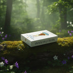 Boîte du jeu « Oracle de la Triade » posée sur une souche couverte de mousse, en forêt avec fleurs et lumière douce.