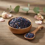 Grains d'encens de résine Padre Pio, mélange de teintes bleu foncé et violet-bourgogne, dans un bol en bois clair avec une cuillère, sur une table en bois.