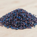 Gros plan sur un monticule de grains d'encens de résine Padre Pio, montrant un mélange dense de bleu électrique, de violet et de noir.