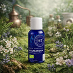 Flacon en verre bleu Herbes et Traditions - Huile Essentielle - Palmarosa Bio entouré de petites fleurs blanches et violettes sur un lit de mousse.