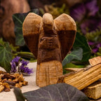 Ange en bois sculpté entouré de bâtons de palo santo brut, bois beige doré sur support naturel.