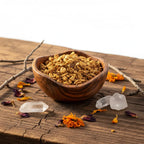Palo santo en copeaux pour fumigation, bois doré-brun dans une coupelle en bois sur table rustique avec cristaux et pétales séchés.