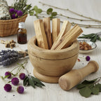 Bâtons de palo santo naturels pour fumigation, bois beige doré dans un mortier en bois avec pilon, entouré de lavande et fleurs séchées.