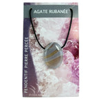 Un pendentif en agate rubanée poli et percé, montrant des bandes naturelles de couleurs grise, brune et blanche, monté sur un cordon noir et présenté sur son emballage cartonné illustré.