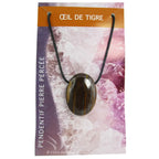 Un pendentif en œil de tigre poli et percé, affichant des reflets chatoyants marron et dorés, monté sur un cordon noir et présenté sur son emballage cartonné illustré.