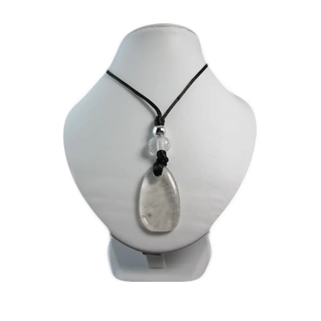Un pendentif en cristal de roche taillé en forme de goutte translucide, orné d'une petite perle argentée et d'une bille de cristal, présenté sur un buste d'exposition blanc.