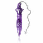Pendule Thot améthyste en pierre naturelle violette sculptée, doté de motifs géométriques gravés et suspendu à une fine chaîne métallique argentée terminée par une perle transparente.