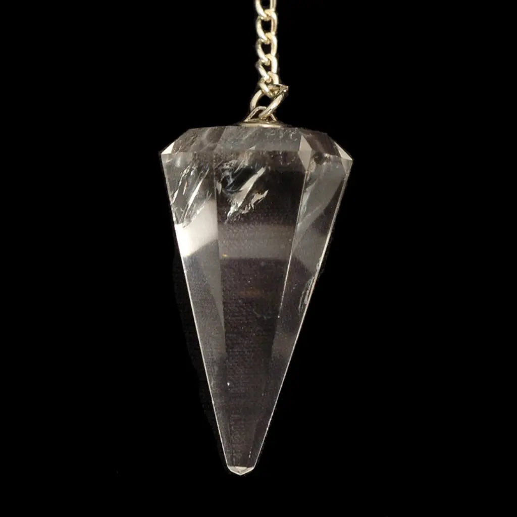 Pendule en cristal de roche taillé en cône à facettes avec chaîne en métal argenté suspendu devant un fond noir.