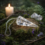 Pendule en forme de cône à facettes en Cristal de Roche translucide posé sur un socle en bois dans une atmosphère rituelle lumineuse.