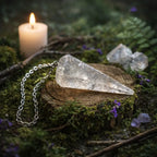 Pendule en forme de cône à facettes en Cristal de Roche translucide avec fines aiguilles de Tourmaline noire, posé sur un rondin de bois moussu dans une atmosphère de forêt sacrée.