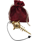 Pendule Planétaire doré en métal avec sphère et anneau posé devant une pochette en tissu rouge.
