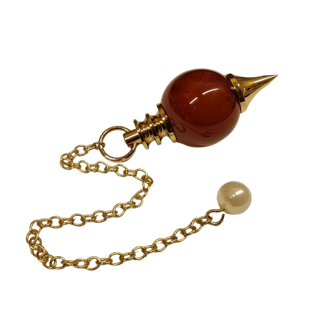 Pendule Séphoroton en cornaline orange avec monture et chaîne en métal doré, terminé par une perle nacrée sur fond blanc.