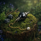 Pendule Sephoroton en Hématite gris anthracite métallique avec monture et chaîne dorées, posé sur une souche moussue dans un décor de forêt mystique.