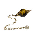 Pendule Séphoroton en œil de tigre brun et métal doré avec chaîne et perle terminale nacrée sur fond blanc.