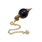 Pendule Séphoroton en sodalite bleu foncé et métal doré avec chaîne et perle terminale blanche sur fond blanc.