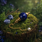 Pendule Sephoroton en Sodalite bleue intense avec monture et chaîne dorées, posé sur une souche de bois moussue dans un décor de forêt mystique.