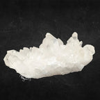 Amas de quartz blanc et translucide aux nombreuses pointes pyramidales de différentes tailles sur fond noir.