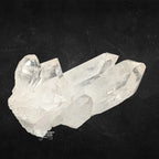 Amas de cristal de roche couché montrant de longues pointes de quartz horizontales sur fond noir.