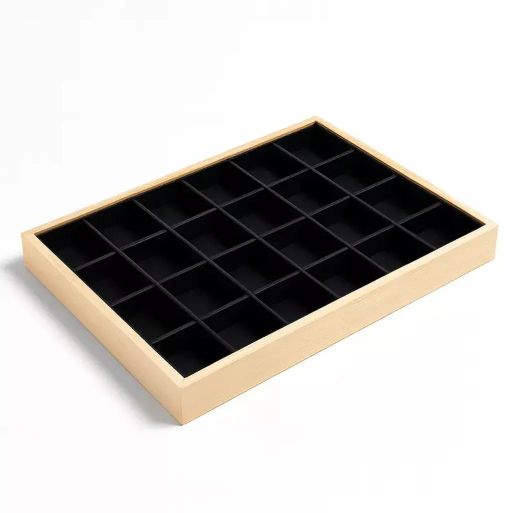 Un plateau de rangement et de présentation en bois clair pour minéraux et cristaux, comprenant 24 compartiments individuels avec un revêtement intérieur noir, présenté sur un fond blanc.