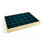 Un plateau de rangement et de présentation en bois clair pour minéraux et cristaux, comprenant 24 compartiments individuels tapissés de feutrine vert canard sur un fond blanc.