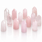 Ensemble de plusieurs pointes en quartz rose poli aux nuances douces, claires et translucides, disposées verticalement sur un fond blanc avec un léger reflet à leur base.