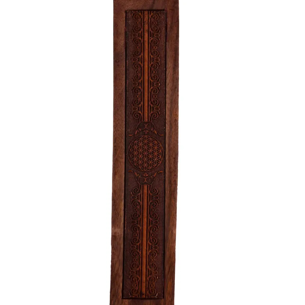 Gros plan d’un porte-encens en bois gravé, avec arabesques et médaillon central « fleur de vie », sur fond blanc.