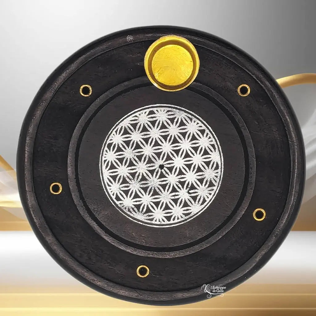 Porte-encens rond noir avec motif « Fleur de Vie » blanc au centre et insert doré pour cône, sur fond clair.