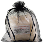 Sachet en organza noir rempli de sels de la Potion de bain Anti-coups de froid sur fond blanc.