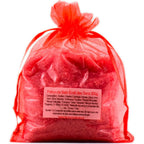 Sachet en organza rouge vif rempli de sels de la Potion de bain Éveil des Sens sur fond blanc.