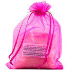 Sachet en organza rose vif rempli de sels de la Potion de bain Tendresse sur fond blanc