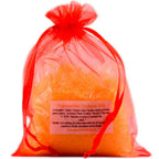 Sachet en organza orange vif rempli de sels de la Potion de bain Tonifiante sur fond blanc.