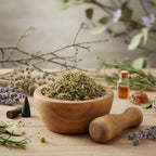 Poudre magique d’argent, mélange d’herbes dans un mortier en bois, entouré de lavande, romarin et résines.