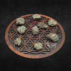 Neuf morceaux de pyrite brute, affichant un éclat métallique doré et une texture cristalline irrégulière, disposés sur une fleur de vie en bois sur fond noir.