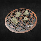 Quatre morceaux de pyrite brute, affichant un éclat métallique doré et une texture cristalline irrégulière, disposés sur une fleur de vie en bois sur fond noir.