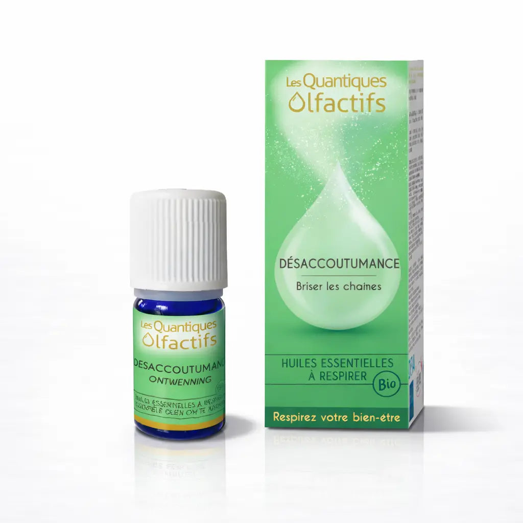 Un flacon de complexe d'huiles essentielles bio "Désaccoutumance" de la gamme Les Quantiques Olfactifs, accompagné de son étui vert pomme, présenté avec son reflet sur un fond blanc.