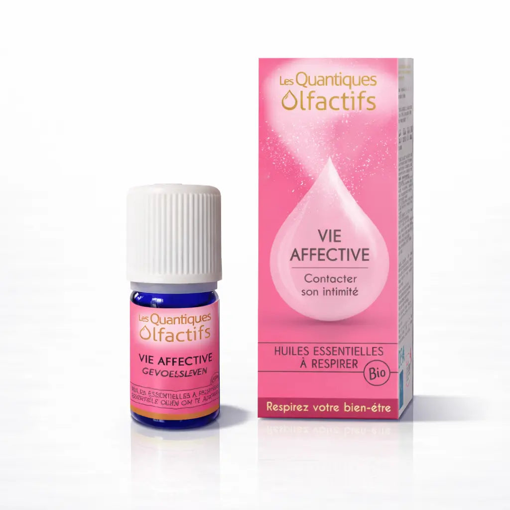 Un flacon de complexe d'huiles essentielles bio "Vie Affective" de la gamme Les Quantiques Olfactifs, accompagné de son étui rose, présenté avec son reflet sur un fond blanc.